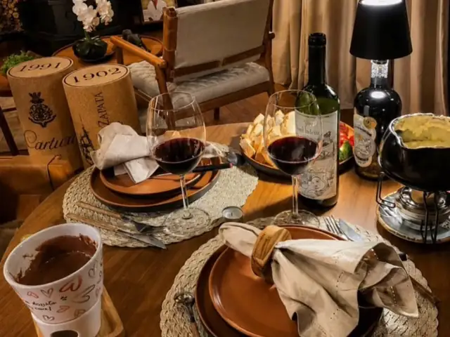 Mesa posta para dois com fondue, vinho e taças