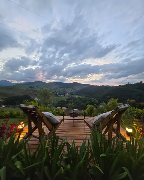 O deck com duas cadeiras de madeira e o fire pit, de frente para o vale ao entardecer