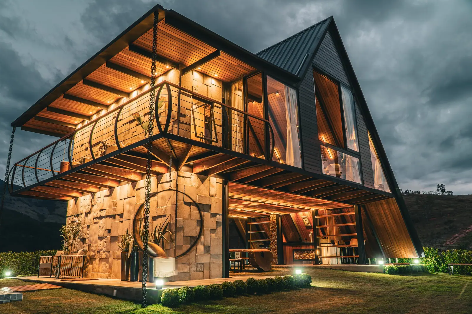 A fachada do Chalé RIVAGI iluminada ao anoitecer, com as montanhas atrás